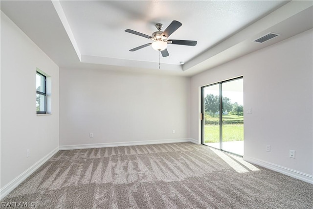 carpeted empty room featuring a tray ceiling and ceiling fan