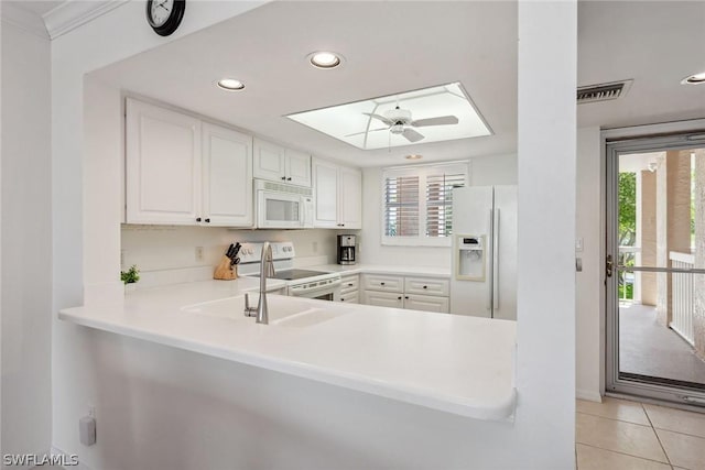 kitchen with white appliances, white cabinets, ceiling fan, light tile patterned flooring, and kitchen peninsula