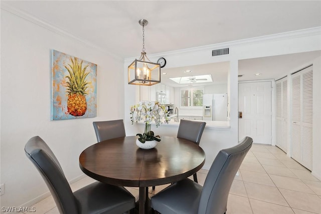 tiled dining area with ceiling fan with notable chandelier, a skylight, and crown molding