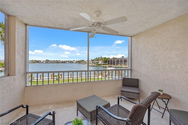 sunroom with ceiling fan and a water view