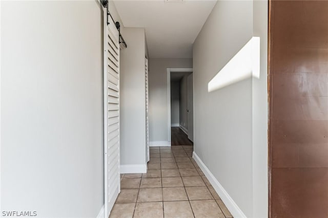 251 Palm Dr Unit 251-2, Naples, FL 34112 - corridor featuring a barn door, light tile patterned floors, and baseboards