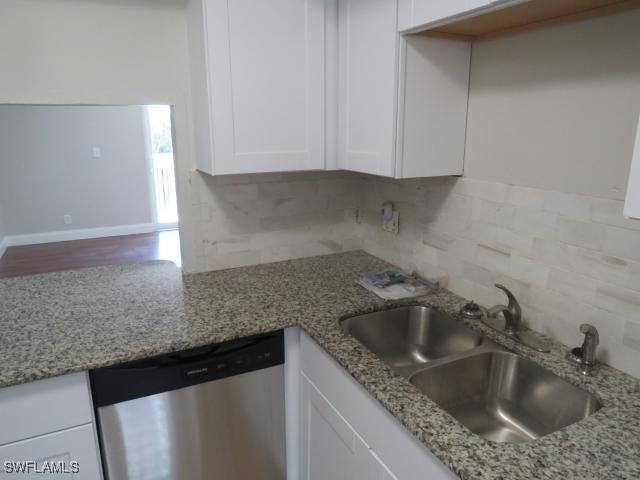 251 Palm Dr Unit 251-2, Naples, FL 34112 - kitchen with dishwasher, a sink, white cabinets, decorative backsplash, and light stone counters