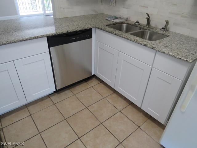 251 Palm Dr Unit 251-2, Naples, FL 34112 - kitchen with stainless steel dishwasher, a sink, tasteful backsplash, white cabinetry, and light tile patterned floors