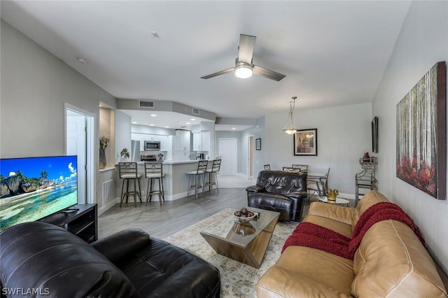 living room with ceiling fan and light hardwood / wood-style flooring