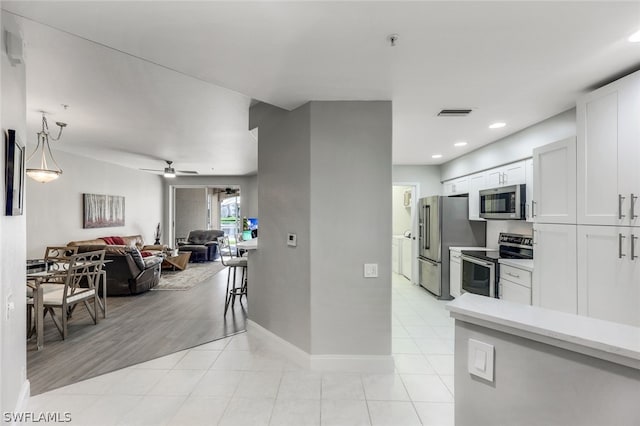 kitchen featuring white cabinets, ceiling fan, decorative light fixtures, light hardwood / wood-style floors, and stainless steel appliances