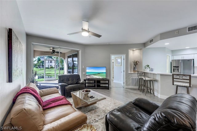 living room with light wood-type flooring and ceiling fan