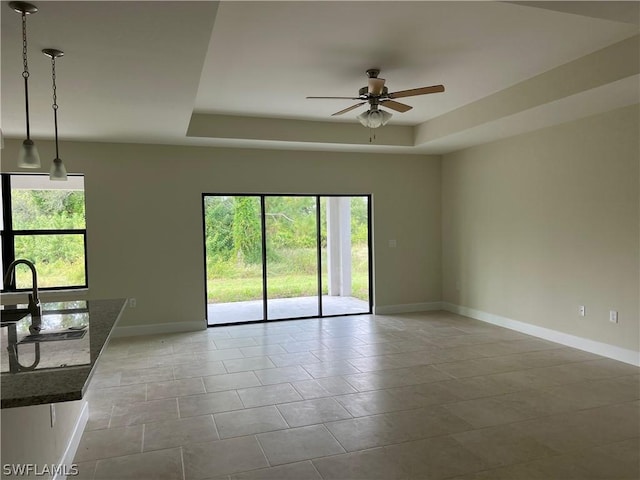 spare room featuring sink, ceiling fan, and a tray ceiling