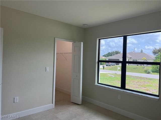 unfurnished bedroom featuring a walk in closet, a closet, and light tile patterned floors