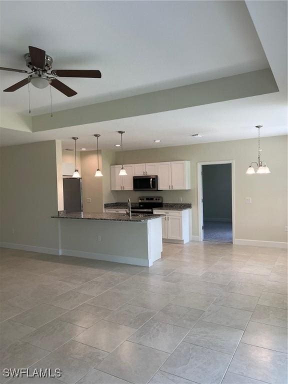 kitchen featuring stainless steel appliances, white cabinets, ceiling fan with notable chandelier, dark stone counters, and hanging light fixtures