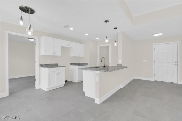 kitchen featuring a sink, white cabinetry, a peninsula, light stone countertops, and recessed lighting