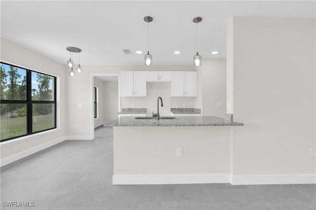 kitchen featuring a sink, light stone countertops, white cabinets, baseboards, and recessed lighting