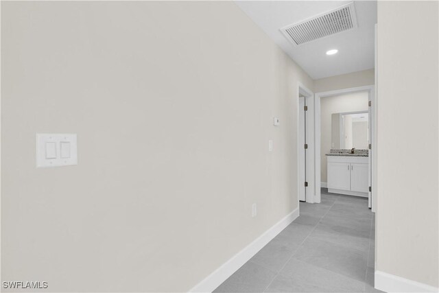 hall with baseboards, a sink, and recessed lighting
