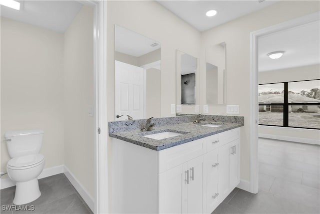bathroom with tile patterned floors, toilet, double vanity, and baseboards