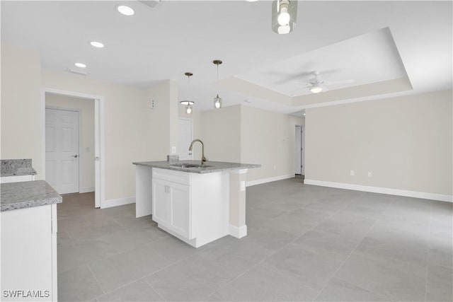 kitchen featuring a sink, a ceiling fan, white cabinets, baseboards, and open floor plan