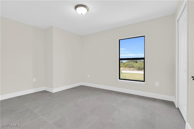 spare room with baseboards and tile patterned flooring