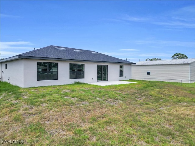 back of property featuring stucco siding, a lawn, a patio, and roof with shingles
