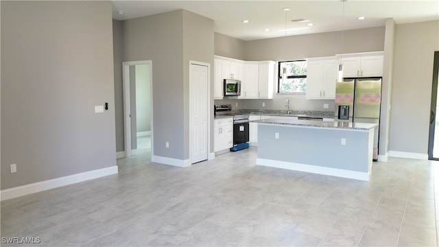 kitchen featuring light stone countertops, white cabinets, a center island, and appliances with stainless steel finishes