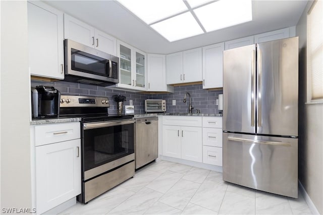 kitchen featuring white cabinetry, sink, stainless steel appliances, and light stone counters