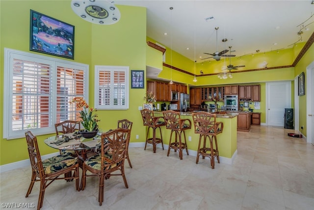 tiled dining space with ceiling fan and a high ceiling