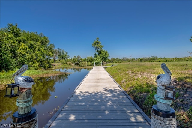 dock area with a water view and a lawn