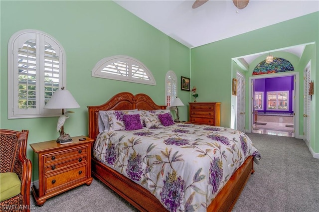 carpeted bedroom with connected bathroom, ceiling fan, and lofted ceiling