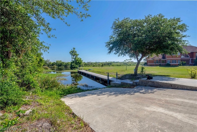 surrounding community with a water view, a yard, and a dock