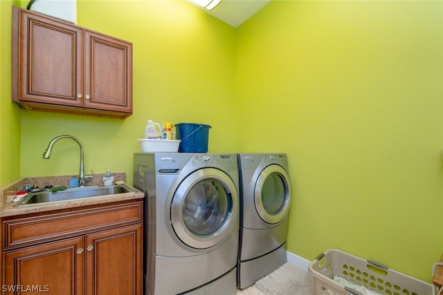 clothes washing area with washer and dryer, sink, and cabinets