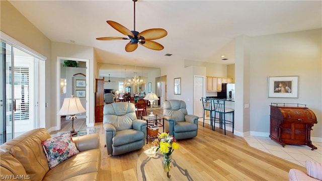 living room featuring light hardwood / wood-style floors and ceiling fan with notable chandelier