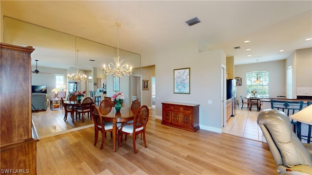 dining space with light hardwood / wood-style flooring and ceiling fan with notable chandelier