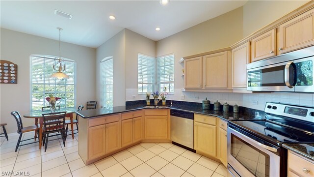 kitchen featuring pendant lighting, decorative backsplash, light brown cabinetry, kitchen peninsula, and stainless steel appliances