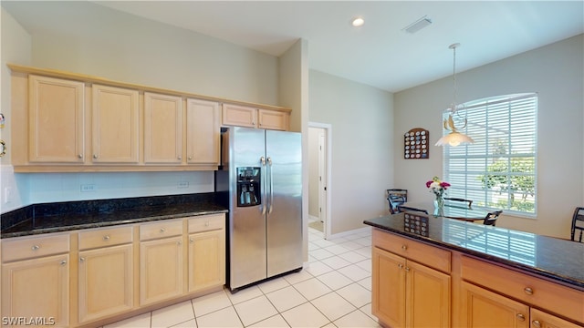 kitchen with stainless steel refrigerator with ice dispenser, decorative light fixtures, light brown cabinetry, and dark stone countertops