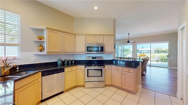 kitchen featuring dark stone counters, sink, ceiling fan, appliances with stainless steel finishes, and kitchen peninsula