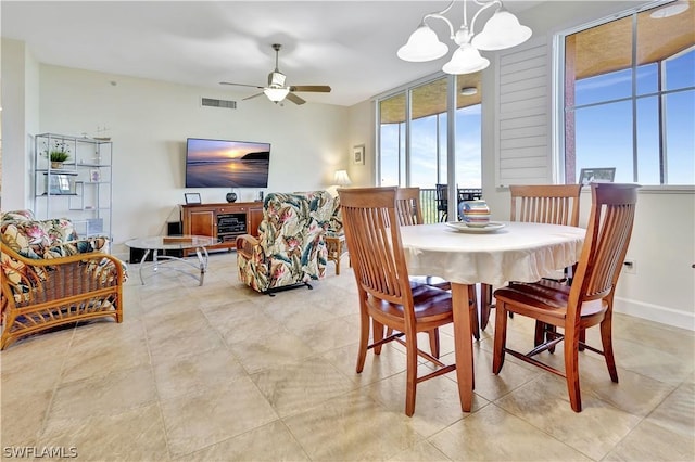 dining room with ceiling fan with notable chandelier, a fireplace, visible vents, and baseboards