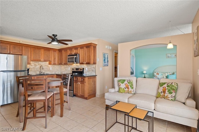 7300 Estero Blvd Unit 301, Fort Myers Beach, FL 33931 - kitchen with appliances with stainless steel finishes, brown cabinetry, ceiling fan, open floor plan, and tasteful backsplash
