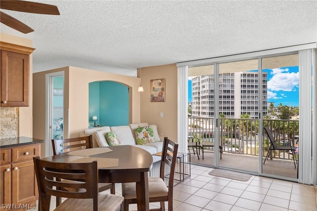 7300 Estero Blvd Unit 301, Fort Myers Beach, FL 33931 - dining room with a wall of windows, a textured ceiling, light tile patterned floors, a ceiling fan, and arched walkways