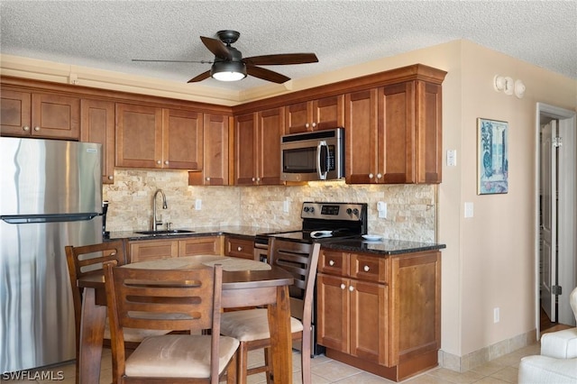 kitchen with a textured ceiling, sink, light tile patterned floors, and stainless steel appliances