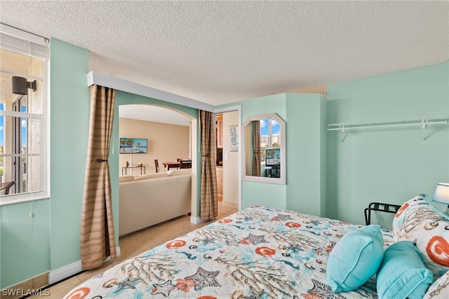 bedroom with a textured ceiling and multiple windows