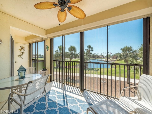 sunroom / solarium featuring a water view and ceiling fan