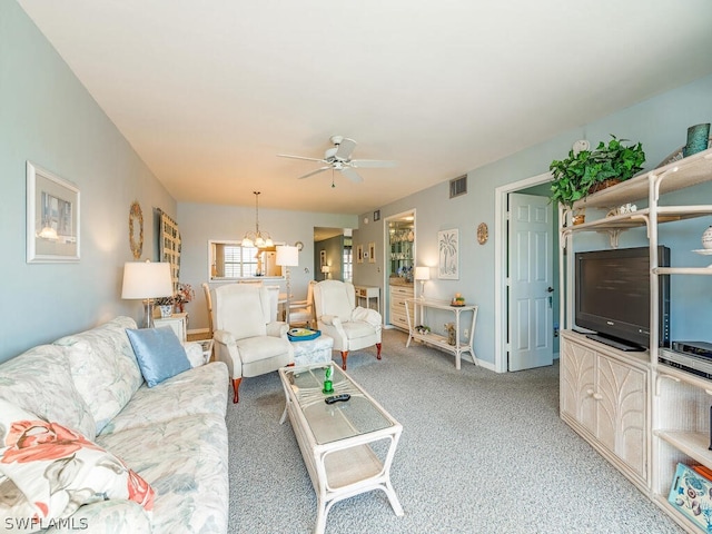 carpeted living room with ceiling fan with notable chandelier