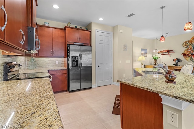 kitchen with tasteful backsplash, sink, hanging light fixtures, light stone countertops, and appliances with stainless steel finishes