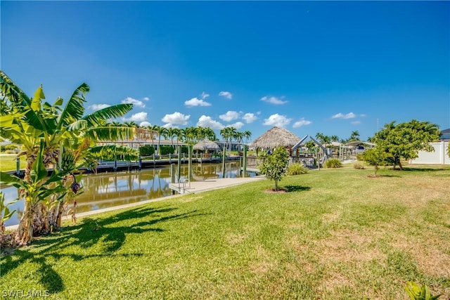 view of home's community with a lawn, a water view, and a boat dock