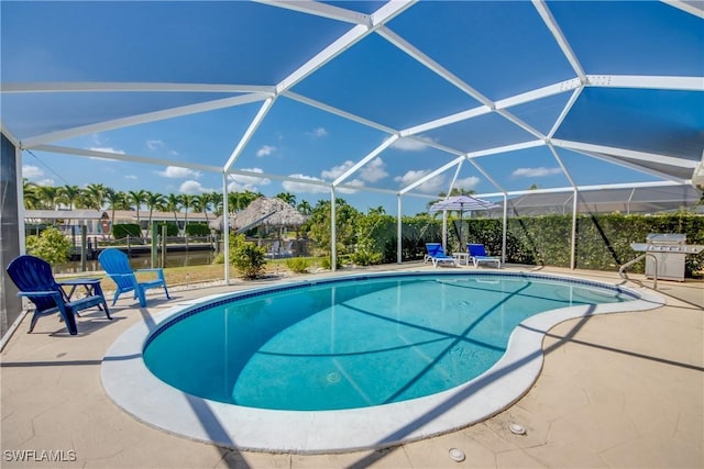 view of swimming pool with a lanai, a patio area, a grill, and a water view