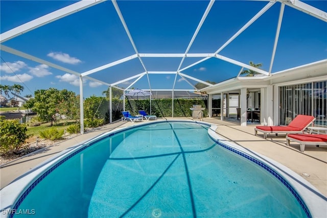 view of pool with glass enclosure and a patio