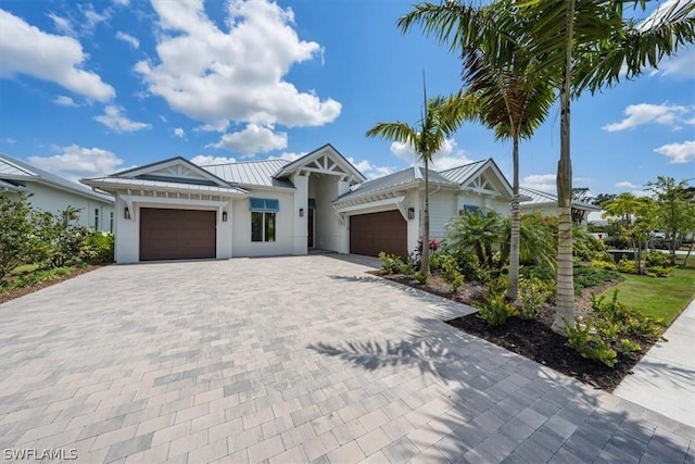 view of front of property with decorative driveway, stucco siding, a standing seam roof, metal roof, and a garage