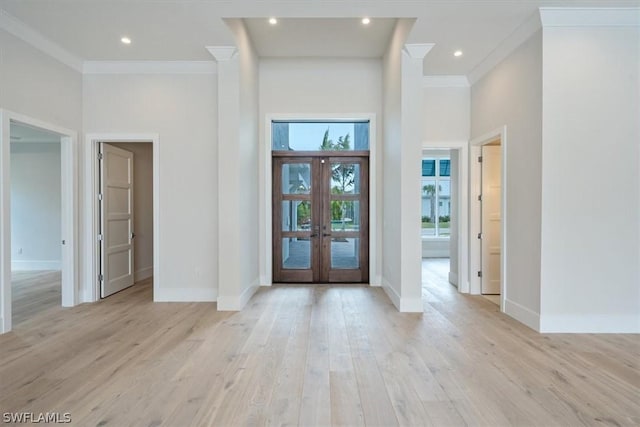 entrance foyer with french doors, a towering ceiling, light hardwood / wood-style floors, and crown molding