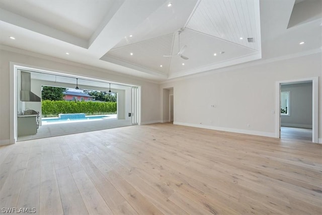 unfurnished living room featuring ceiling fan, light hardwood / wood-style floors, a raised ceiling, and ornamental molding