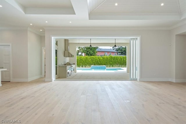 unfurnished living room with a raised ceiling, crown molding, and light hardwood / wood-style flooring