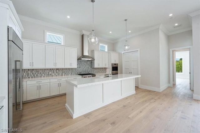 kitchen with wall chimney exhaust hood, white cabinetry, appliances with stainless steel finishes, and light hardwood / wood-style flooring