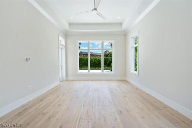 unfurnished room featuring light wood-type flooring, a raised ceiling, and ceiling fan