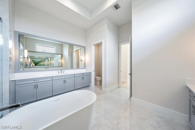 bathroom with vanity, a tub to relax in, and toilet